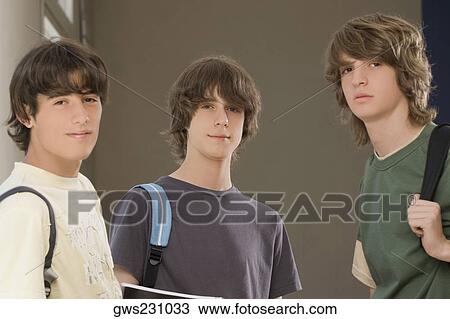 Stock Image - Portrait of two teenage boys standing with a young man. Fotosearch