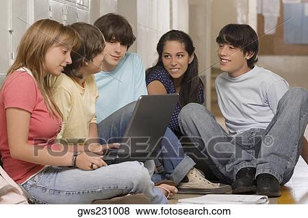 Side profile of a teenage girl using a laptop with her friends sitting beside her View Large Photo Image Stock Photo - Side profile of a teenage girl using a laptop with her friends sitting beside her. Fotosearch