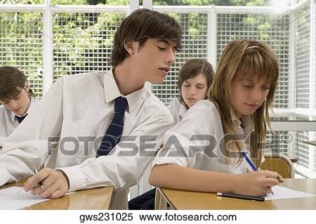 Young man peeping into a teenage girl's examination sheet View Large Photo Image Stock Photography - Young man peeping into a teenage girl's examination sheet. Fotosearch