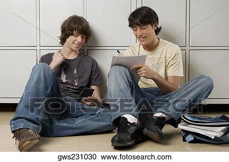 Young man sitting with a teenage boy and writing on a notebook View Large Photo Image Stock Image - Young man sitting with a teenage boy and writing on a notebook. Fotosearch