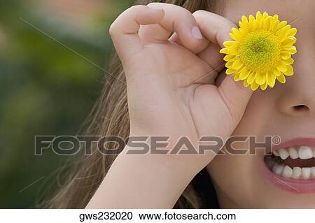 Close-up of a girl holding a flower on her eye View Large Photo Image Stock Image - Close-up of a girl holding a flower on her eye. Fotosearch