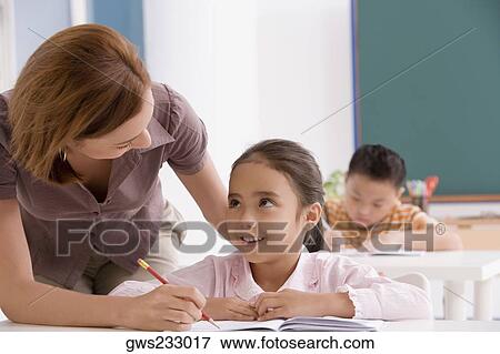 Close-up of a female teacher teaching a schoolgirl in a classroom View Large Photo Image Stock Photo - Close-up of a female teacher teaching a schoolgirl in a classroom. Fotosearch