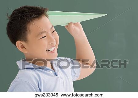 Stock Photography - Close-up of a schoolboy playing with a paper airplane. Fotosearch