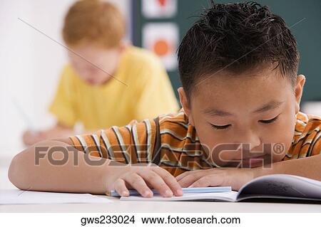 Close-up of a schoolboy reading a book in a classroom View Large Photo Image Picture - Close-up of a schoolboy reading a book in a classroom. Fotosearch