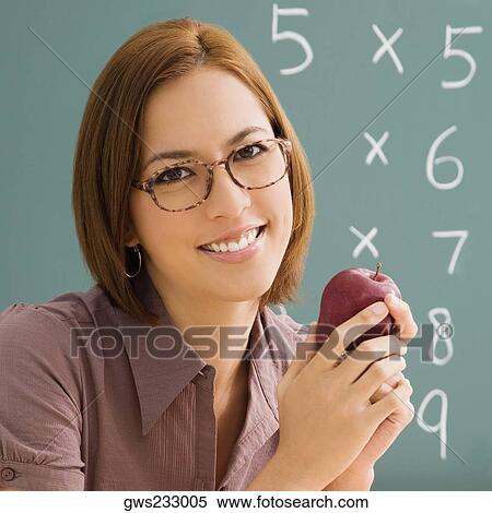 Stock Photography - Portrait of a female teacher holding an apple and smiling. Fotosearch