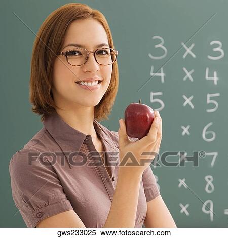 Stock Photography - Portrait of a female teacher holding an apple and smiling. Fotosearch