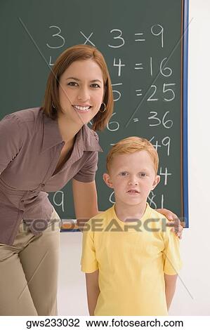 Portrait of a schoolboy standing with his female teacher in a classroom View Large Photo Image Stock Image - Portrait of a schoolboy standing with his female teacher in a classroom. Fotosearch