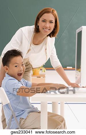 Portrait of a schoolboy with his female teacher in front of a computer View Large Photo Image Stock Image - Portrait of a schoolboy with his female teacher in front of a computer. Fotosearch