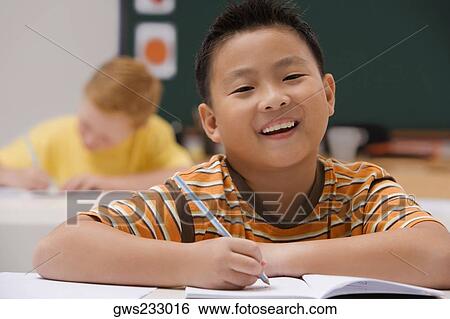 Portrait of a schoolboy writing on a notebook with a pencil and smiling View Large Photo Image Stock Photograph - Portrait of a schoolboy writing on a notebook with a pencil and smiling. Fotosearch