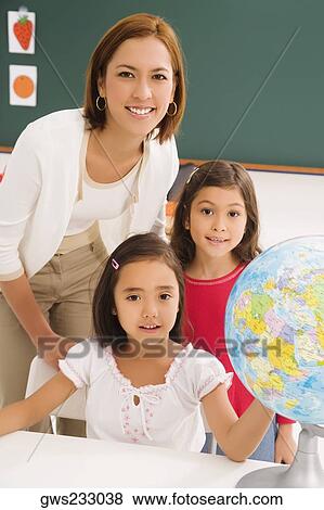 Portrait of two schoolgirls with her female teacher in a classroom View Large Photo Image Stock Photo - Portrait of two schoolgirls with her female teacher in a classroom. Fotosearch
