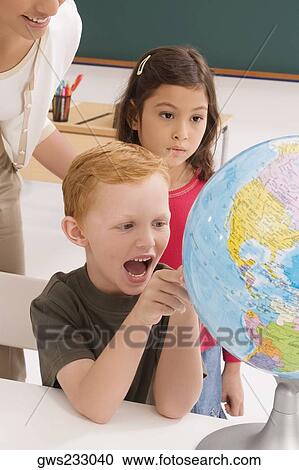 Schoolboy looking at a globe and shouting with a schoolgirl and a female teacher standing behind him View Large Photo Image Stock Image - Schoolboy looking at a globe and shouting with a schoolgirl and a female teacher standing behind him. Fotosearch