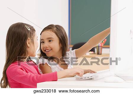 Side profile of two schoolgirls smiling in front of a computer View Large Photo Image Stock Photo - Side profile of two schoolgirls smiling in front of a computer. Fotosearch