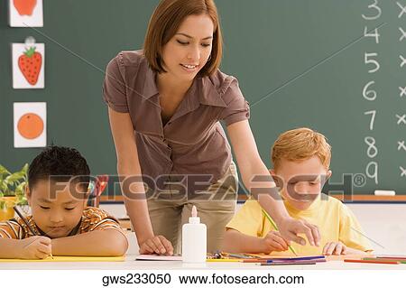 Two schoolboys with their female teacher in a classroom View Large Photo Image Stock Image - Two schoolboys with their female teacher in a classroom. Fotosearch