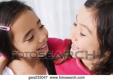 Two schoolgirls looking at each other and smiling in a classroom View Large Photo Image Stock Photo - Two schoolgirls looking at each other and smiling in a classroom. Fotosearch