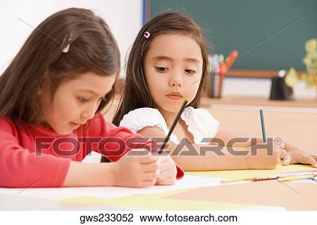 Stock Image - Two schoolgirls painting in an art class. Fotosearch