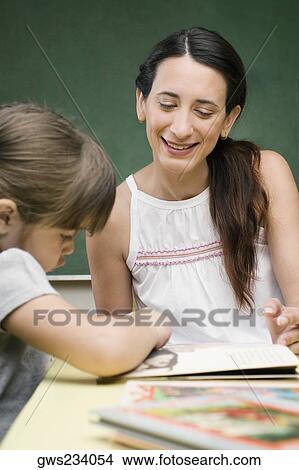 Female teacher teaching her student in a classroom View Large Photo Image Picture - Female teacher teaching her student in a classroom. Fotosearch