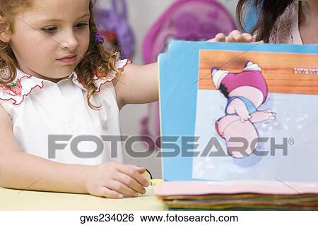 Girl looking at drawings View Large Photo Image Stock Photograph - Girl looking at drawings. Fotosearch