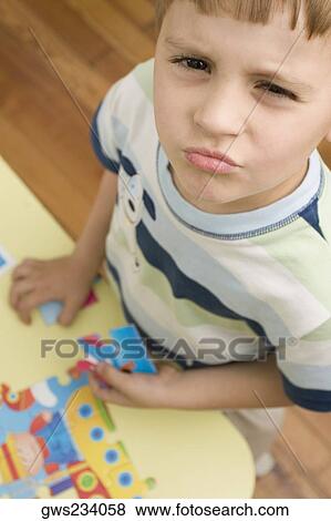 Stock Photo - Portrait of a boy holding a puzzle piece. Fotosearch