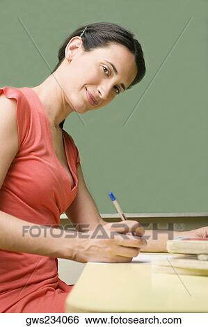 Portrait of a mid adult woman writing with a pen on a sheet of paper View Large Photo Image Stock Photograph - Portrait of a mid adult woman writing with a pen on a sheet of paper. Fotosearch