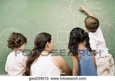 Rear view of a female teacher teaching her students View Large Photo Image Stock Image - Rear view of a female teacher teaching her students. Fotosearch