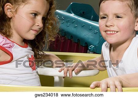 Side profile of a boy and a girl sitting in a toy car View Large Photo Image Stock Photo - Side profile of a boy and a girl sitting in a toy car. Fotosearch