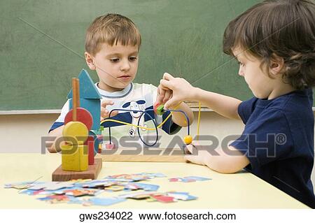 Stock Image - Two boys playing with a buzz wire game. Fotosearch