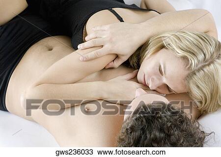Stock Image - High angle view of a young couple lying on the bed. Fotosearch