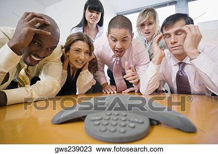 Business executives looking at the conference phone View Large Photo Image Stock Image - Business executives looking at the conference phone. Fotosearch