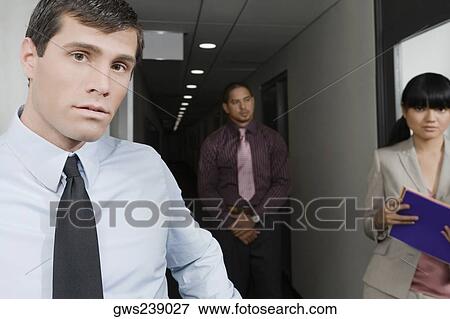 Stock Photo - Business executives standing in a corridor in an office. Fotosearch