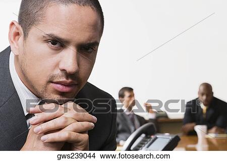 Close-up of a businessman with his colleagues discussing in the background View Large Photo Image Picture - Close-up of a businessman with his colleagues discussing in the background. Fotosearch