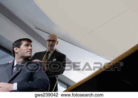 Low angle view of two businessmen in an office View Large Photo Image Stock Image - Low angle view of two businessmen in an office. Fotosearch
