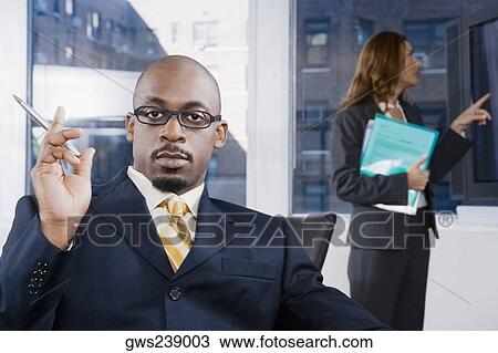 Portrait of a businessman thinking with a businesswoman standing in the background View Large Photo Image Stock Image - Portrait of a businessman thinking with a businesswoman standing in the background. Fotosearch