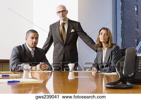 Stock Image - Portrait of two businessmen with a businesswoman in an office. Fotosearch