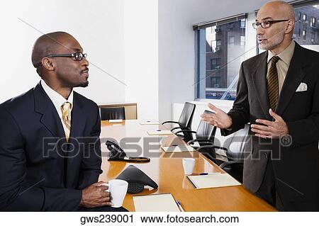 Stock Image - Two businessmen discussing in a conference room. Fotosearch