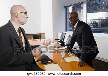 Two businessmen discussing in a conference room View Large Photo Image Stock Photo - Two businessmen discussing in a conference room. Fotosearch