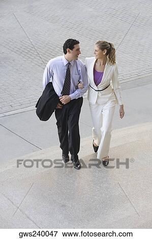 Businessman and a businesswoman moving up on steps with their arm in arm View Large Photo Image Stock Photo - Businessman and a businesswoman moving up on steps with their arm in arm. Fotosearch
