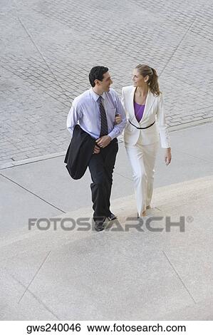 Businessman and a businesswoman moving up on steps with their arm in arm View Large Photo Image Stock Photograph - Businessman and a businesswoman moving up on steps with their arm in arm. Fotosearch