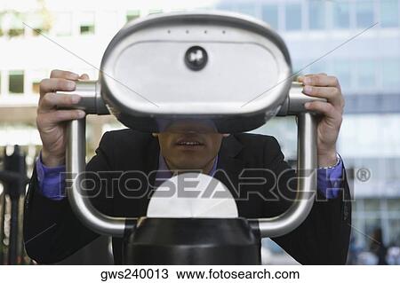 Businessman looking through a coin-operated binoculars View Large Photo Image Stock Image - Businessman looking through a coin-operated binoculars. Fotosearch