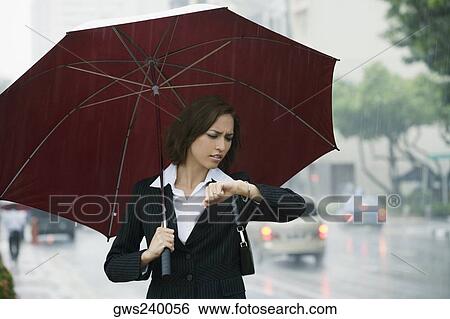 Businesswoman checking the time during rain View Large Photo Image Stock Photograph - Businesswoman checking the time during rain. Fotosearch
