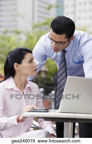 Businesswoman using a laptop with a businessman standing beside her View Large Photo Image Stock Photo - Businesswoman using a laptop with a businessman standing beside her. Fotosearch