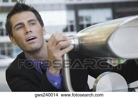 Close-up of a businessman holding a coin-operated binoculars View Large Photo Image Picture - Close-up of a businessman holding a coin-operated binoculars. Fotosearch