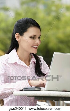 Close-up of a businesswoman using a laptop and smiling View Large Photo Image Stock Image - Close-up of a businesswoman using a laptop and smiling. Fotosearch
