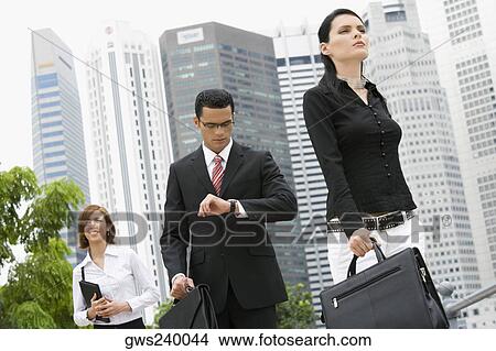 Two businesswomen and a businessman walking in front of buildings View Large Photo Image Picture - Two businesswomen and a businessman walking in front of buildings. Fotosearch
