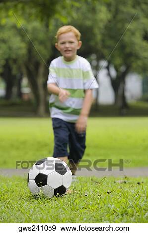 Stock Photo - Boy playing football in a park. Fotosearch