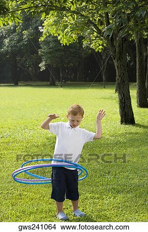 Boy playing with a plastic hoop in a park View Large Photo Image Picture - Boy playing with a plastic hoop in a park. Fotosearch