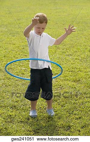 Stock Image - Boy playing with a plastic hoop in a park. Fotosearch