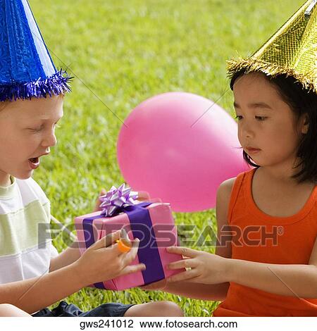 Close-up of a boy giving a birthday present to a girl View Large Photo Image Stock Image - Close-up of a boy giving a birthday present to a girl. Fotosearch