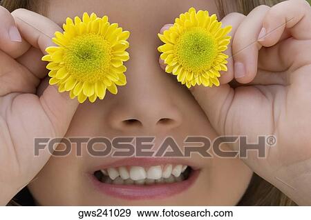 Close-up of a girl covering her eyes with flowers View Large Photo Image Stock Photo - Close-up of a girl covering her eyes with flowers. Fotosearch