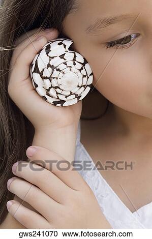 Close-up of a girl holding a spiral seashell close to her ear View Large Photo Image Stock Image - Close-up of a girl holding a spiral seashell close to her ear. Fotosearch