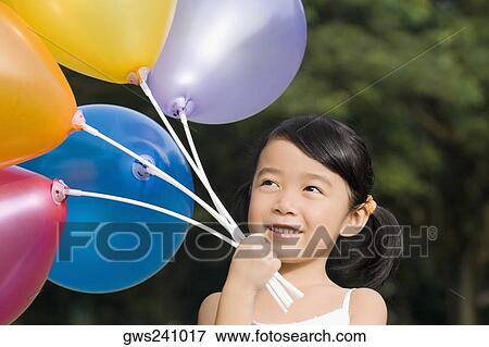 Close-up of a girl holding balloons View Large Photo Image Stock Photo - Close-up of a girl holding balloons. Fotosearch